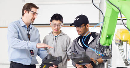 Teacher instructing students how to use robotic arm