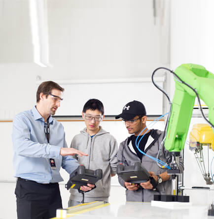 Teacher instructing students how to use robotic arm